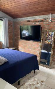 a bedroom with a blue bed and a flat screen tv at Casa de campo in Itapema