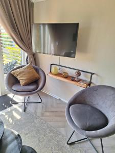two chairs sitting in a living room with a tv at Woodlonge Tinyhouse in Lathum