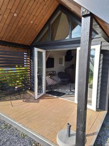 a screened in porch with a wooden deck at Woodlonge Tinyhouse in Lathum +14 photos