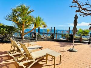 eine Gruppe von Stühlen und ein Sonnenschirm und das Meer in der Unterkunft Best4U Nautico in San Miguel de Abona