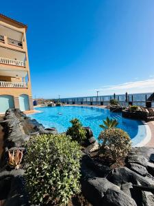 ein Pool neben einem Gebäude und dem Meer in der Unterkunft Best4U Nautico in San Miguel de Abona