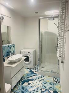 a bathroom with a shower and a washing machine at Apartament Zielona in Mysłakowice
