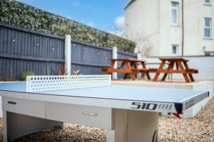 a ping pong table in a backyard with two picnic tables at Large home in Cardiff's city center - 14 Beds in Cardiff