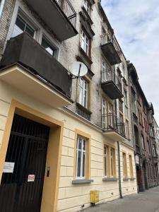 a building with a black door and windows on a street at Przytulny apartament in Chorzów