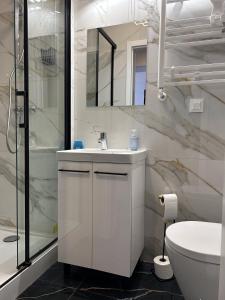 a white bathroom with a sink and a shower at Przytulny apartament in Chorzów