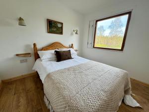 a bedroom with a large bed with a window at Solstice Cabin in Torlundy