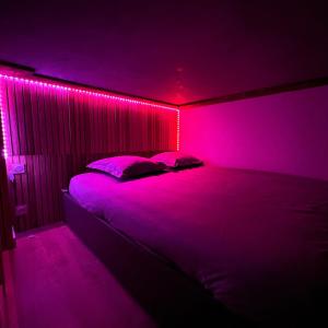a bedroom with a bed with pink lights on it at Appart Massage Relax - Studio in Morbier +6 photos