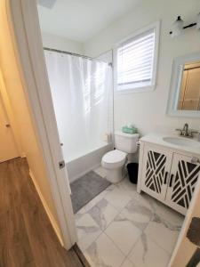 a white bathroom with a toilet and a sink at Lakewoodlyon Park Renovated Cottage Near Duke 26b in Durham