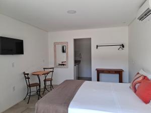 a bedroom with a bed and a table and chairs at Pontal Flats in Paraty
