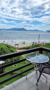 a table and chair on a balcony overlooking a beach at Pousada Rosauros in Palhoça +6 photos