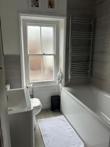a bathroom with a tub and a toilet and a window at Single Room in Georgian Masionette in Blandford Forum
