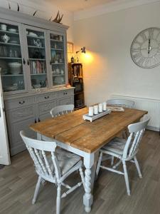 a dining room table with chairs and a clock on the wall at Single Room in Georgian Masionette in Blandford Forum