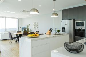 a white kitchen with a table with a bowl of fruit at Casa da Lombada in Ponta do Sol