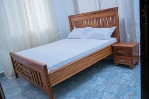 ein Holzbett mit einem Holzrahmen und einem Nachttisch in der Unterkunft Entire home in Mlole, Kigoma, Tanzania in Gungu