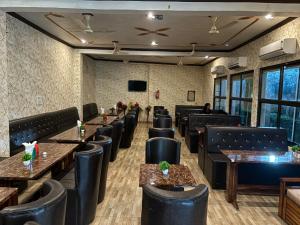 Pura RaghunāthHotel Dawat的餐厅设有黑色的桌椅和平面电视。