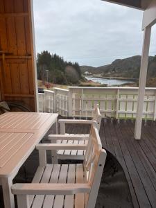 a porch with two white benches and a table at Fjærestua in Hitra