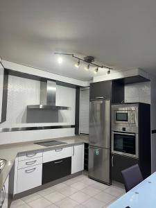 a kitchen with stainless steel appliances and white cabinets at PISO Bueu Playa in Bueu