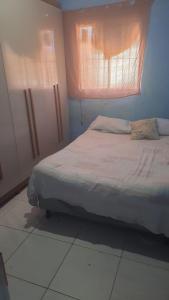 a bedroom with a bed with a window and a white floor at Casa para Carnaval in Olinda