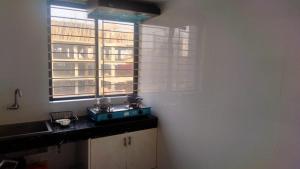 a kitchen with a sink and two windows in it at Airport Bliss Residence in Chandālbhog