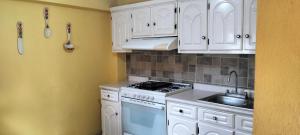 a kitchen with white cabinets and a stove and a sink at Casa Tlatlauqui in Tlatlauquitepec