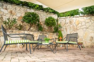 three chairs and a table in front of a stone wall at Residence Chiesiola in Vieste