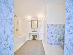ein weißes Badezimmer mit einem Waschbecken, einer Badewanne und einem Spiegel in der Unterkunft Luxurious Studio Vasiliki in Hydra + 13 Fotos