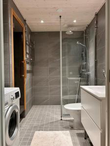 a bathroom with a shower toilet and a washing machine at Cozy Central Apartment with Sauna in Oulu