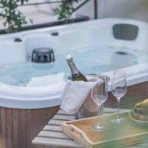 a bath tub with a bottle of champagne and two wine glasses at Bahal dell'Etna Agri-Resort in Ramacca