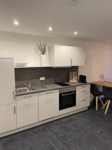 a kitchen with white cabinets and a sink and a table at Urlaub-WeinhofHerrenberg 2 in Schoden