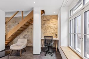 Ein Büro mit Schreibtisch und Stühlen neben einer Steinmauer in der Unterkunft The R Apartment Rosengasse in Schaffhausen