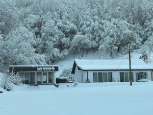 ein schneebedecktes Gebäude vor einem Wald in der Unterkunft Lay House in Şuncuiuş