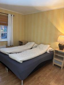 a bed in a bedroom with a lamp and a window at Fjærestua in Hitra