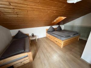 two beds in a room with a wooden ceiling at Reiheneckhaus mit Garten und Terasse in Tettnang