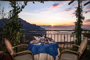 a table with plates of food on a balcony with the sunset at B&B Ravello Rooms in Ravello