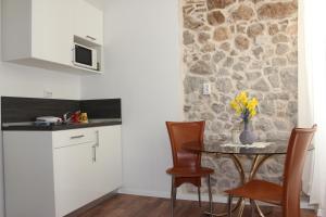 kuchnia ze stołem i krzesłami oraz kamienną ścianą w obiekcie City Break Dubrovnik Apartments w Dubrowniku