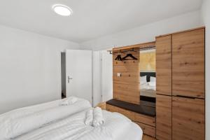 a bedroom with two white beds and a wooden cabinet at The R Apartment Cholfirst in Schaffhausen
