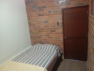 a bed in a room next to a brick wall at Gardenias Suites Ambuquí Valle de la Eterna Juventud in Hacienda Opote