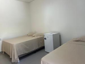 a bedroom with two beds and a small refrigerator at Su House Suíte Arraial dAjuda in Porto Seguro