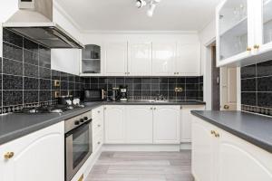 a kitchen with white cabinets and black tiles at Modern One Bedroom Duplex Apartment - Central Oxford in Oxford +9 photos