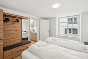 a white bedroom with two beds and a window at The R Apartment Randen in Schaffhausen
