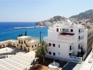 een groot wit gebouw naast een waterlichaam bij White House Hotel-Apart in Karpathos