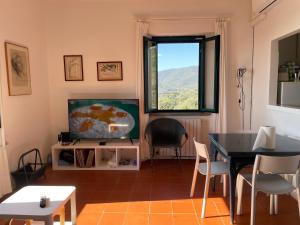 a living room with a television and a table and chairs at Antica Casa Prile in Castiglione della Pescaia