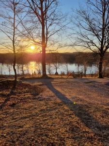 a sunset over a body of water with trees at Skogsgläntan in Åshuvud