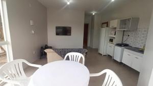 a white kitchen with a table and white chairs at Apartamento com Vista Panorâmica in São Gabriel +1 photo