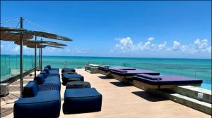 a row of chaise lounges on a beach with the ocean at Apartamento Beira Mar NEW TIME 1014 in Maceió