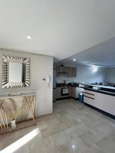 カサブランカにあるLuxury 2 bedroom flat in Tamaris Dar Bouazzaの白いキャビネットと鏡付きの広いキッチン