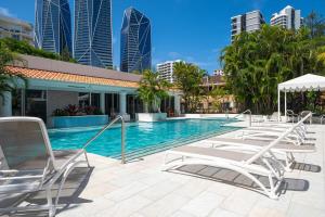 a swimming pool with lounge chairs and buildings at 1BR Tropical Escape with Heated Pools Sauna BBQ in Gold Coast