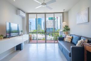 a living room with a blue couch and a large window at 1BR Tropical Escape with Heated Pools Sauna BBQ in Gold Coast