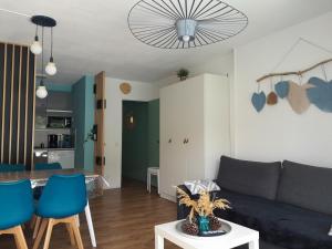 a living room with a couch and a table at Bleu Océan - Sur le port Appartement avec piscine, terrasse, parking in Capbreton