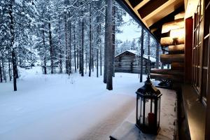 Eine Laterne auf der Veranda einer Hütte im Schnee in der Unterkunft Pikkukelo Levi - Doorstep Ski Bus - Sauna - Traditional log cabin in Levi
